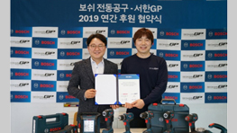 보쉬 프로페셔널 도구 앞에서 계약서를 들고 있는 두 남성의 사진.