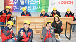 보쉬 마스터 행사에서 헬멧을 쓴 사람들이 목공 작업을 하고 있다.