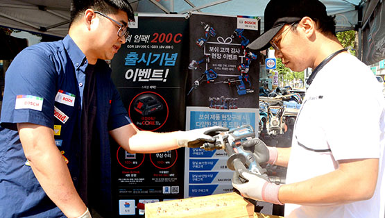 보쉬 전문가 도구를 시연하는 두 남성이 야외에서 대화하고 있다.