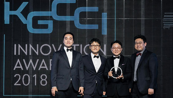 네 명의 남성이 정장 차림으로 상을 들고 있습니다. 배경은 어두운 색상입니다.